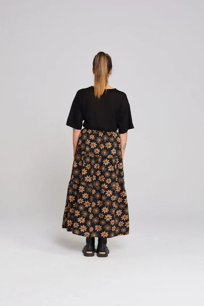 Person wearing a black floral skirt and black top on a white background