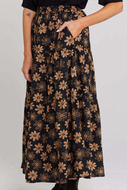 Black skirt with brown floral pattern worn by a person on a plain background